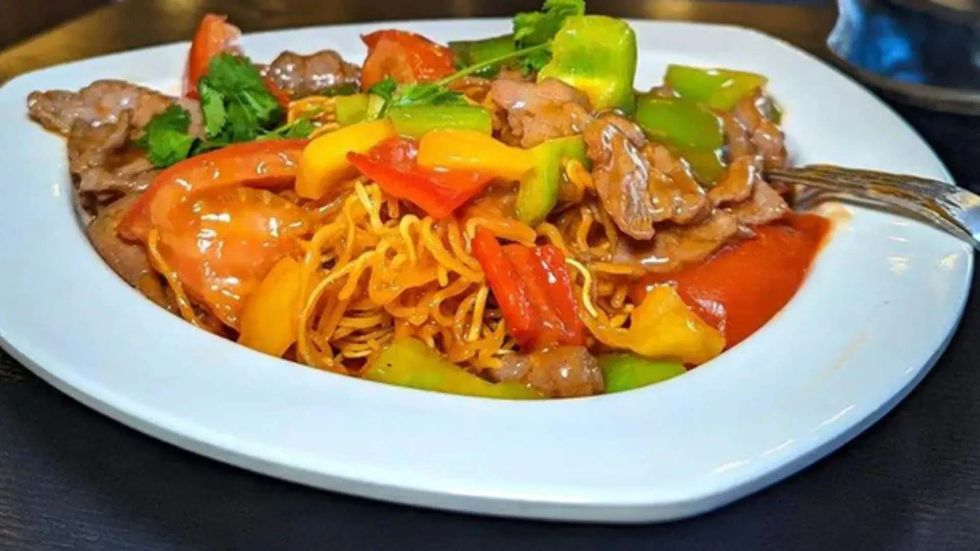 Pan fried beef noodle stir fry with colorful bell pepper strips at Smile House Cafe, a Hong Kong Style Fast Food Restaurant in San Francisco