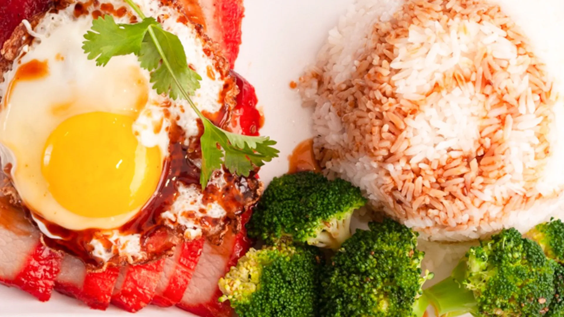 Grilled pork neck rice bowl topped with runny sunny side egg and broccoli at Smile House Cafe, a Hong Kong Style Fast Food Restaurant in San Francisco