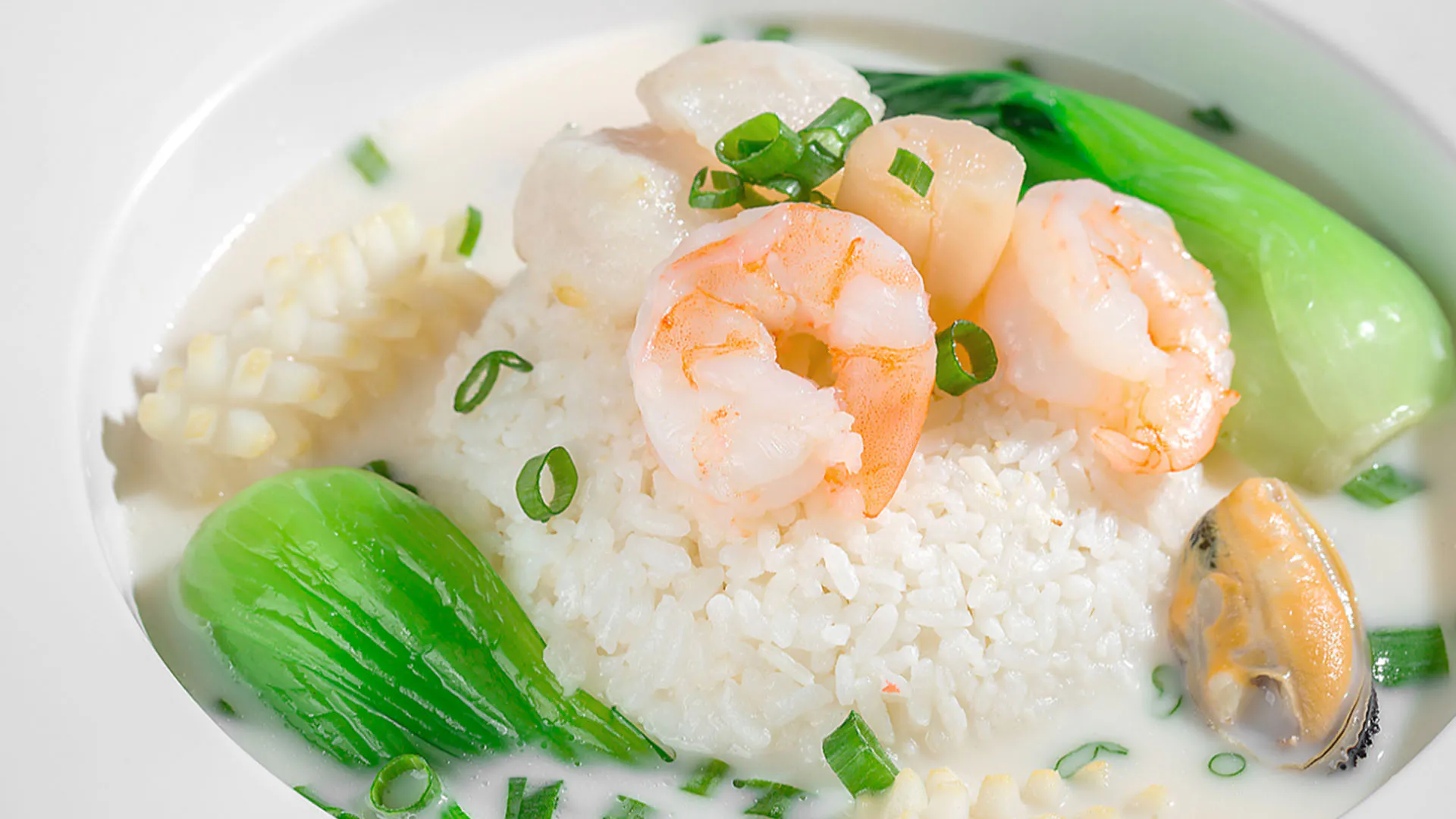 Creamy seafood congee with shrimp, mussels and fresh bok choy at Smile House Cafe, a Hong Kong Style Fast Food Restaurant in San Francisco