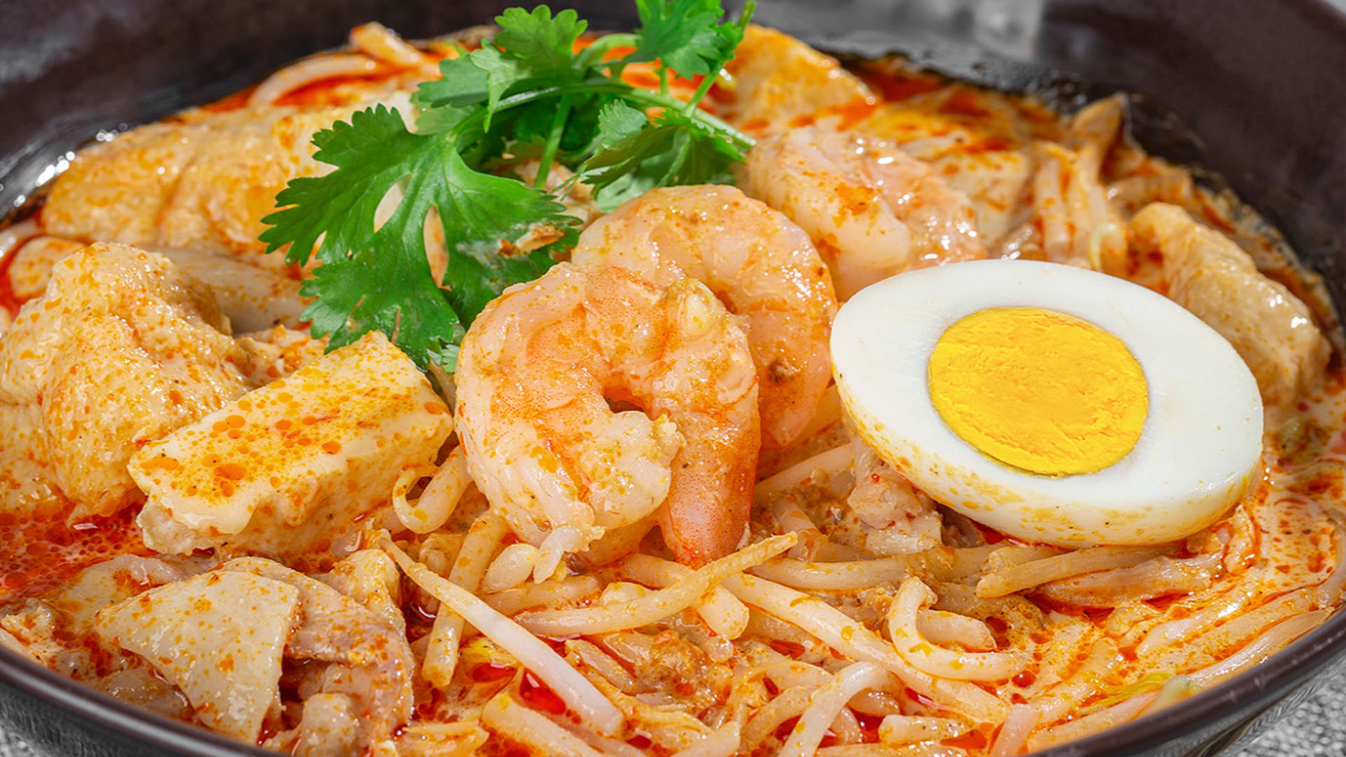 Rich Singapore laksa noodle soup with shrimp, fried tofu and boiled egg at Smile House Cafe, a Hong Kong Style Fast Food Restaurant in San Francisco