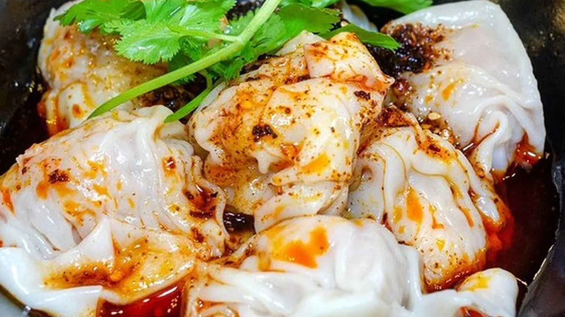 Spicy steamed pork wontons coated in savory chili oil sauce at Smile House Cafe, a Hong Kong Style Fast Food Restaurant in San Francisco